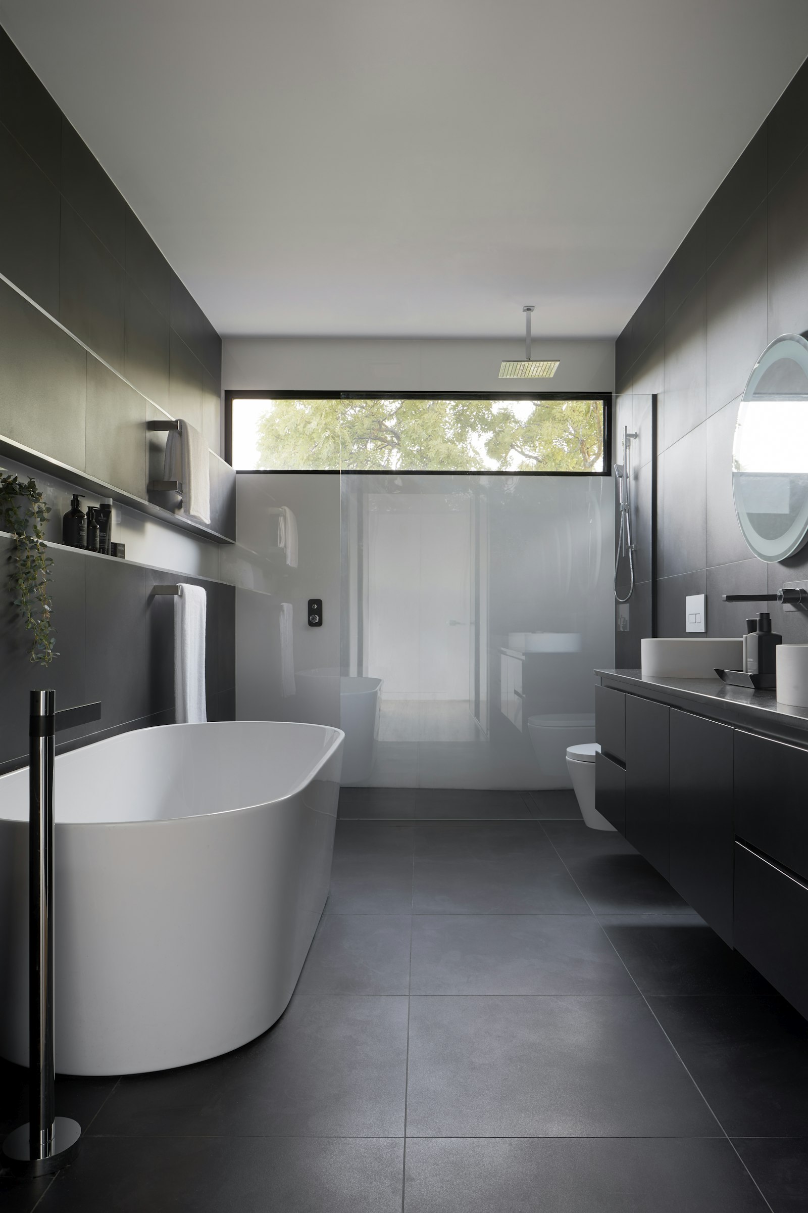 Dark-tile bathroom remodel with a freestanding tub and large shower