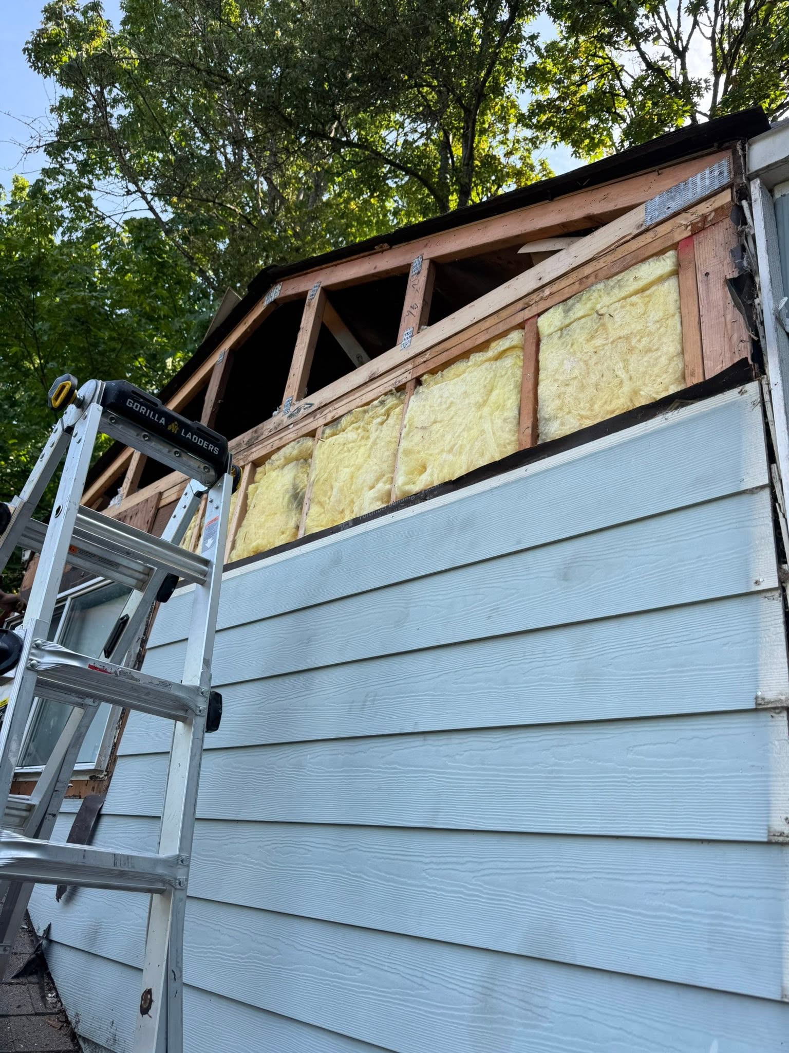 Fiberglass insulation installed in an open gable wall above new siding