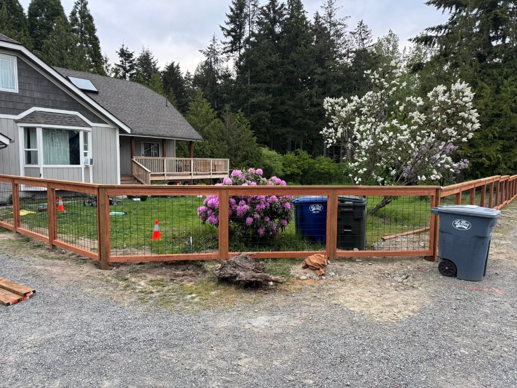 New wood and wire-mesh fence with matching deck railing at a residential property